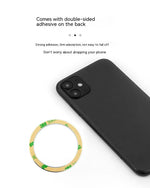 anneau MagSafe Apple avec la partie adhésive et un iPhone noir à côté sur fond blanc