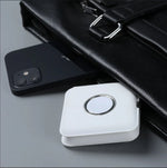 chargeurs double magsafe Apple blanc plié avec un iPhone qui sortent à moitié d’une sacoche en cuire noir posé sur un bureau gris