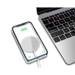 chargeur magnétique iphone samsung universel argenté avec un iPhone 12 en charge sans fil à côté d'un MacBook sur fond blanc